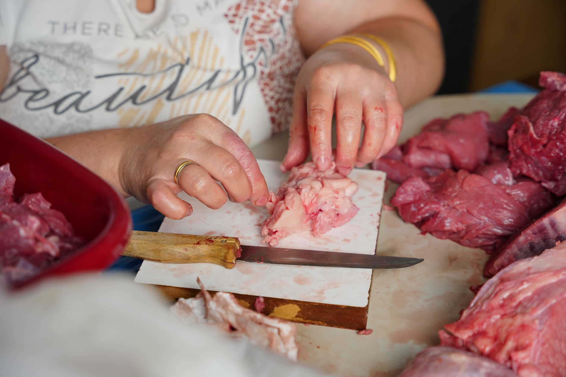 Butcher trimming bone-in and boneless pork cuts on a stainless steel table